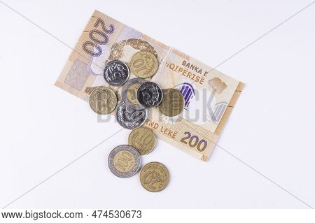 Some Coins And A Lek Banknote Of Albanian Currency On A White Surface