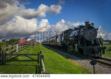 Ronks, Pennsylvania, July 19, 2022 - A Restored Antique Steam Passenger Train Approaches A Fence Wit