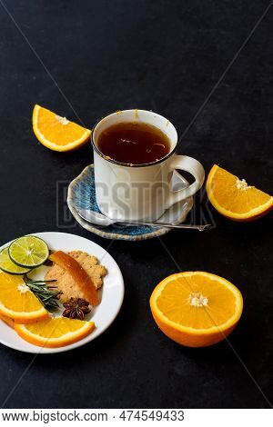Orange Cinnamon Tea With Crystalized Fruits And Cookies On Black Bacground