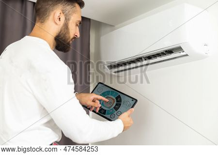 Young Technician Using Digital Tablet And Pen Checking Air Conditioner In House Room. Air Conditioni