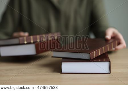 Woman Puts Thick Books Of History With Brown Hardcover On Wooden Table. Librarian Gives Material To 