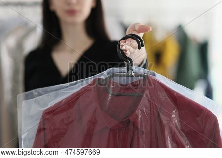 Outstretched Hand Of Woman Holding Hanger With Dry-cleaned Dress Under Film In Dry Cleaning. Manager