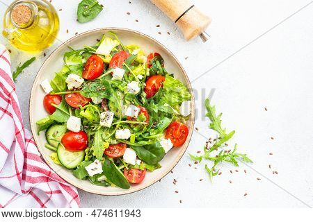 Spring Salad In Craft Plate. Spinach, Arugula, Tomatoes And Feta With Olive Oil. Top View On White.