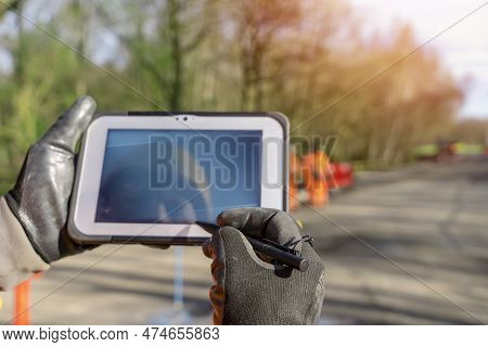 Site Engineer Operating His Touch Screen Controller Tablet During Roadworks. Builder Using Touch Scr