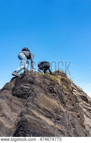 Couple Of Man And Woman Climbing A Small Mountain To Contemplate The Landscape From Above, Ribadesel