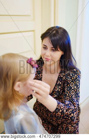 A Cute Little Girl In A Plaid Dress And Mom Primping.