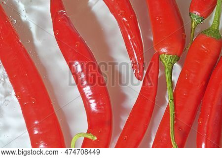Close-up View Of The Red Chilli Peppers In Water Background. Texture Of Cooling Vegeteble Drink With
