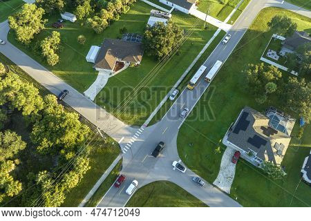 Aerial View Of American Yellow School Bus Picking Up Children At Sidewalk Bus Stop For Their Lessong