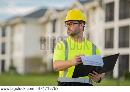 Engineer With Clipboard, Building Inspection. Builder At Construction Site. Buider With Helmet On Co