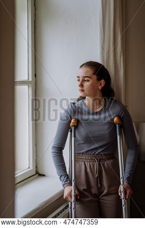 Teenage Girl With Broken Leg Looking Trough Window.