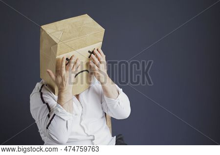 A Sad Man In A White Shirt With A Bag On His Head, With A Drawn Sad Emoticon Is Afraid, Closes His E