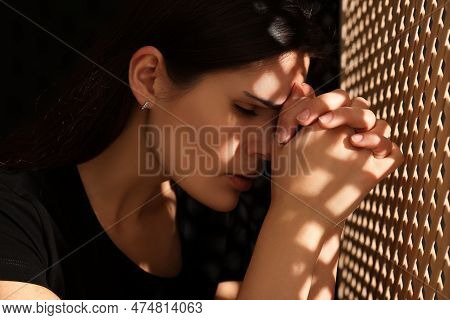 Upset Woman Listening To Priest During Confession In Booth