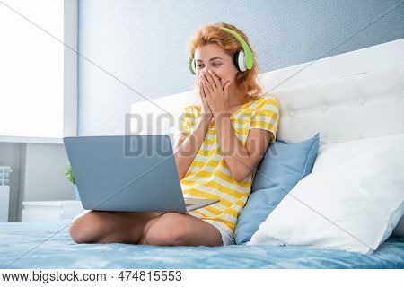 Shocked Woman In Headphones Has Webinar. Woman At Home Watch Webinar. Woman Having Webinar On Laptop