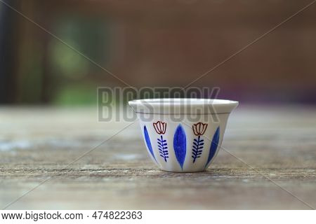 A Traditional Lebanese Coffee Cup Against A Natuaral Brown Background.