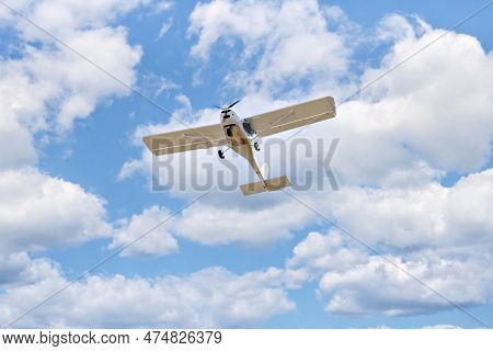 Single Engine Ultralight Plane Flying In The Blue Sky With White Clouds