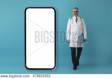 Handsome Grey-haired Doctor Posing By Huge Phone With White Screen