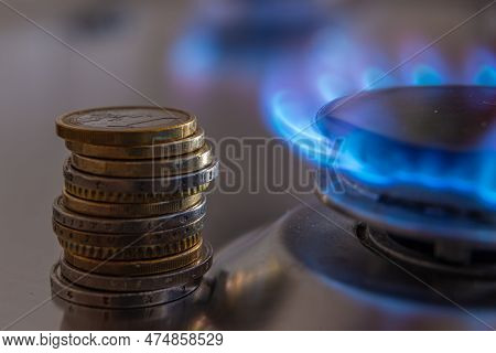 Gas Stove Lit, With Stacks Of Coins Above It. Increase In Gas Costs And Tariffs.
