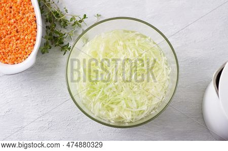 Glass Bowl With Chopped Cabbage Poured With Boiling Water, Baking Dish With Red Lentils, Bunch Of Fr