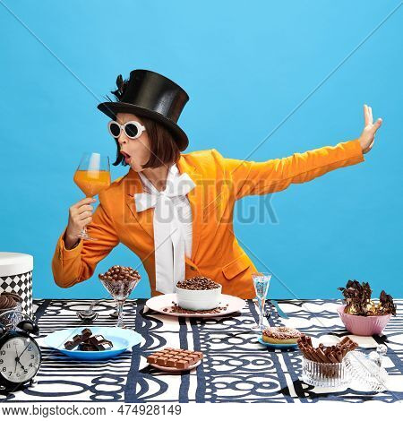 Impressive, Eccentric Woman In Stylish Clothes, Cylinder And Sunglasses, Drinking Juice Over The Tab