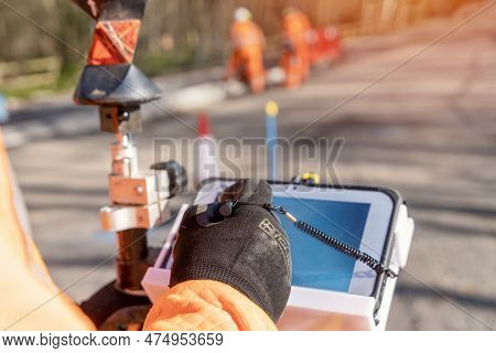 Site Engineer Operating His Instrument During Roadworks. Builder Using Total Positioning Station Tac