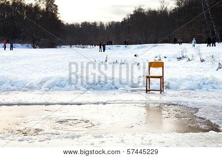 Icebound Chair Near Opening Water In Frozen Lake