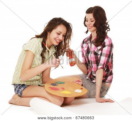 Two beautiful girls with a brush and  palette, sittting