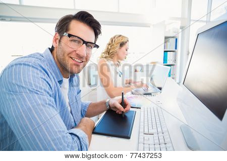 Designer using a graphics tablet while looking at camera in office