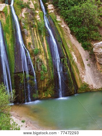 Unusual three-jet waterfall. Three parallel stream running down the steep slope and fall into the oval pool