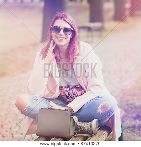 Trendy young woman with pink hair and sunglasses in park
