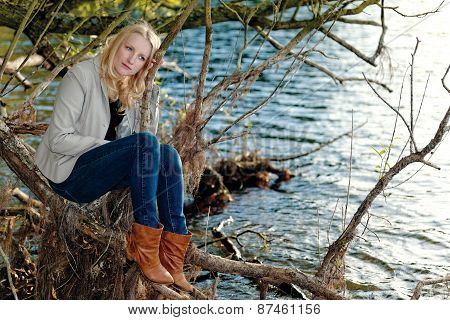 Blond melancholic woman sitting by a lake