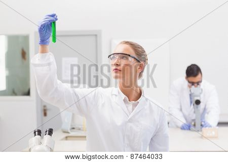 Scientist examining green precipitate in tube in the laboratory