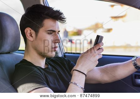 Distracted Young Man Using Cell Phone While Driving a Car
