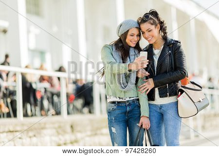 Two Young Women Looking At The Phone While Being Close To Eatch Other