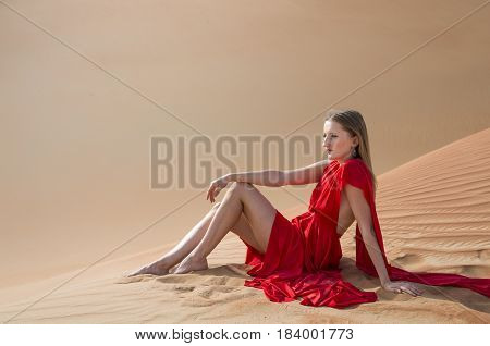 Young and beautiful woman in a red dress in a desert