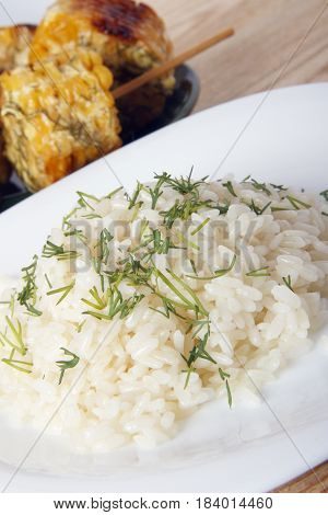 Corn cobs cooked on a grill on a wooden background. Corncobs on wooden skewers with rice