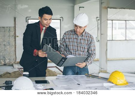 Management consulting with engineers working with blueprint and drawing on work table in for management business plan and construction site project.