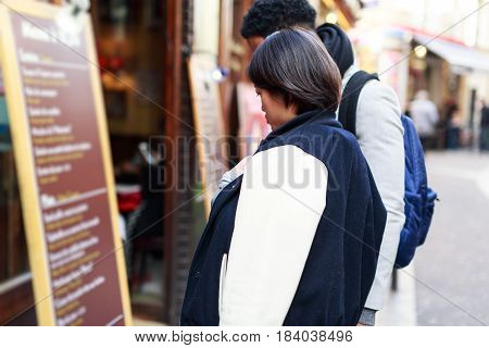 Multi-ethnic couple having fun in Paris, Latin Quarter, near Notre Dame Cathedral. Looking at a restaurant's menu.