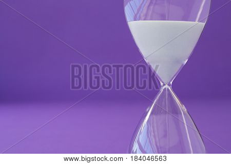 Close-up of hourglass against purple background