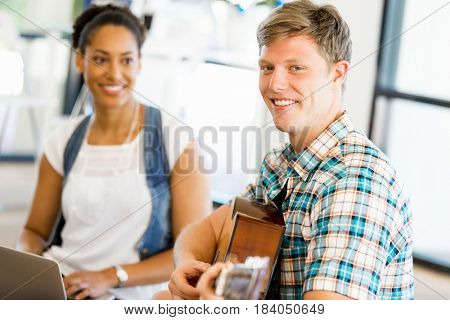 Students sitting on the floor with one playng guitar