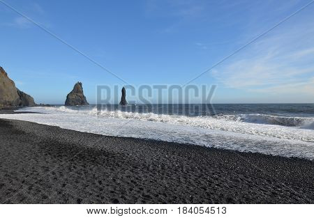 Towering black sea stacks located off the shore of Reynisfjara Beach in Iceland.