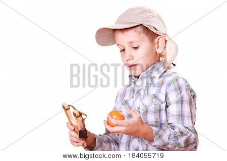 Nature and free time prankster little boy. Child have fun with wooden sling shot and fruit hold orange.