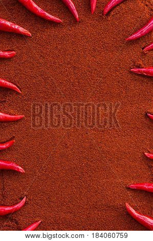 chili red hot pepper, concept of popular spice - sharp tips of red chili peppers laid out in a frame on background of dry mix of brown curry powder, flat lay, top view, free space for text