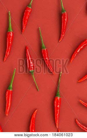 red hot chili peppers, popular spices concept - close-up on beautiful red hot chili peppers filled red background, green tails, collage of freely lying peppers, top view, flat lay