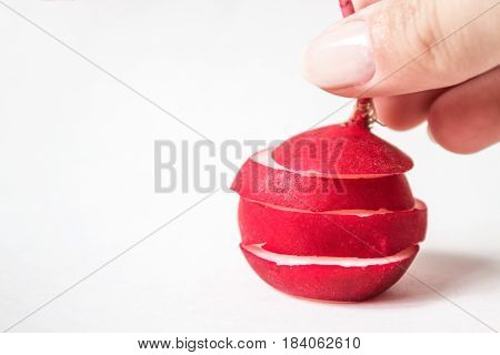 Sliced single radish on a white background and female hand