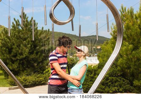Couple of travelers at the symbol of love and happiness in the park Abrau Durso