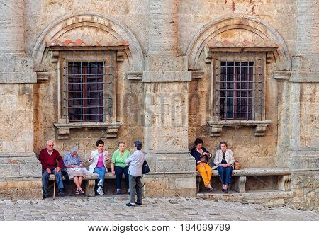 Elderly locals rest and chat under ancient arches on the Town Square Piazza Grande of Montepulciano - Tuscany, Italy, 27 September 2011