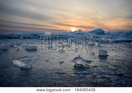 Abstract frozen winter sunrise seascape with ice and colored the sky.