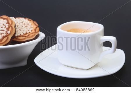 Classic espresso in white cup with homemade cake on black background. Selective focus