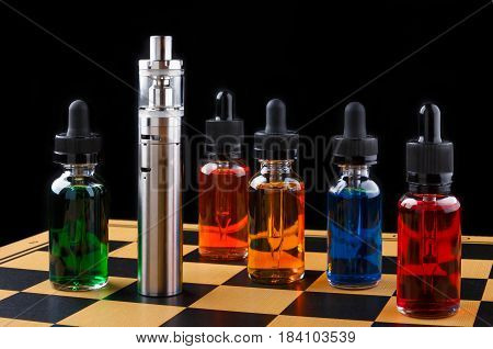 Electronic cigarette and bottles with assorted vape liquid on chessboard and black background