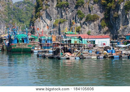 Floating fishing village with rock island in background, Ha Long bay, Vietnam.
